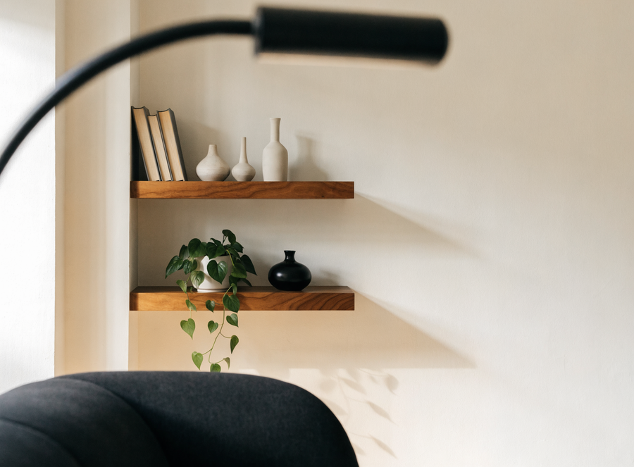 Repisas flotantes de madera en una pared crema con jarrones y una planta